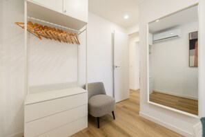 Una habitación moderna con armario empotrado, zona de estar y un espejo grande.