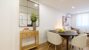 Un espace repas moderne avec une table en bois, des chaises blanches et un vase rempli de fleurs.