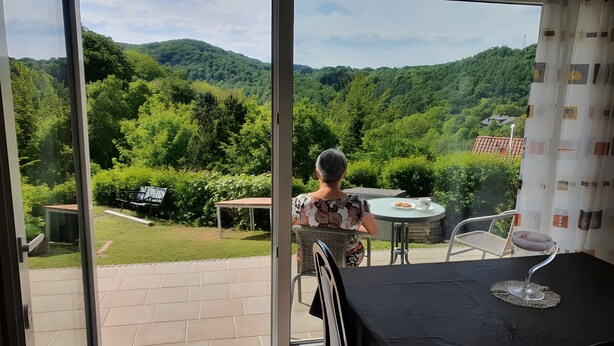 Ein Balkon mit Blick auf eine üppige, grüne Landschaft und einem Tisch mit einem Weinglas.