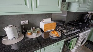 A kitchen with a stove, oven, and a washing machine. There are cups and a plate with food on the counter. - POOL TABLE/ CINEMA ROOM/ WEEKLY DISCOUNTS (Glasgow)