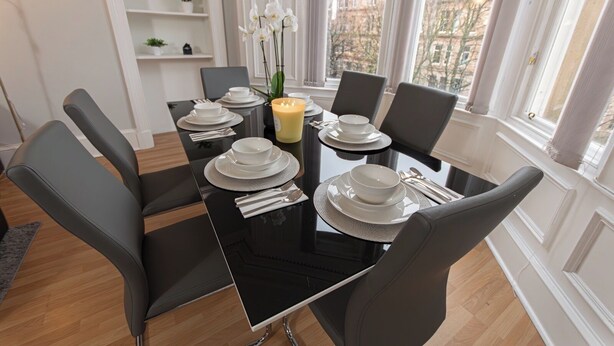 A modern dining room with a black table set for four, white plates, and a candle. - POOL TABLE/ CINEMA ROOM/ WEEKLY DISCOUNTS (Glasgow)