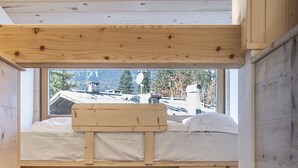 A bunk bed room with a window view of a house and trees. - Poligrafica 1 House, quiet and comfortable (Cortina d´Ampezzo)