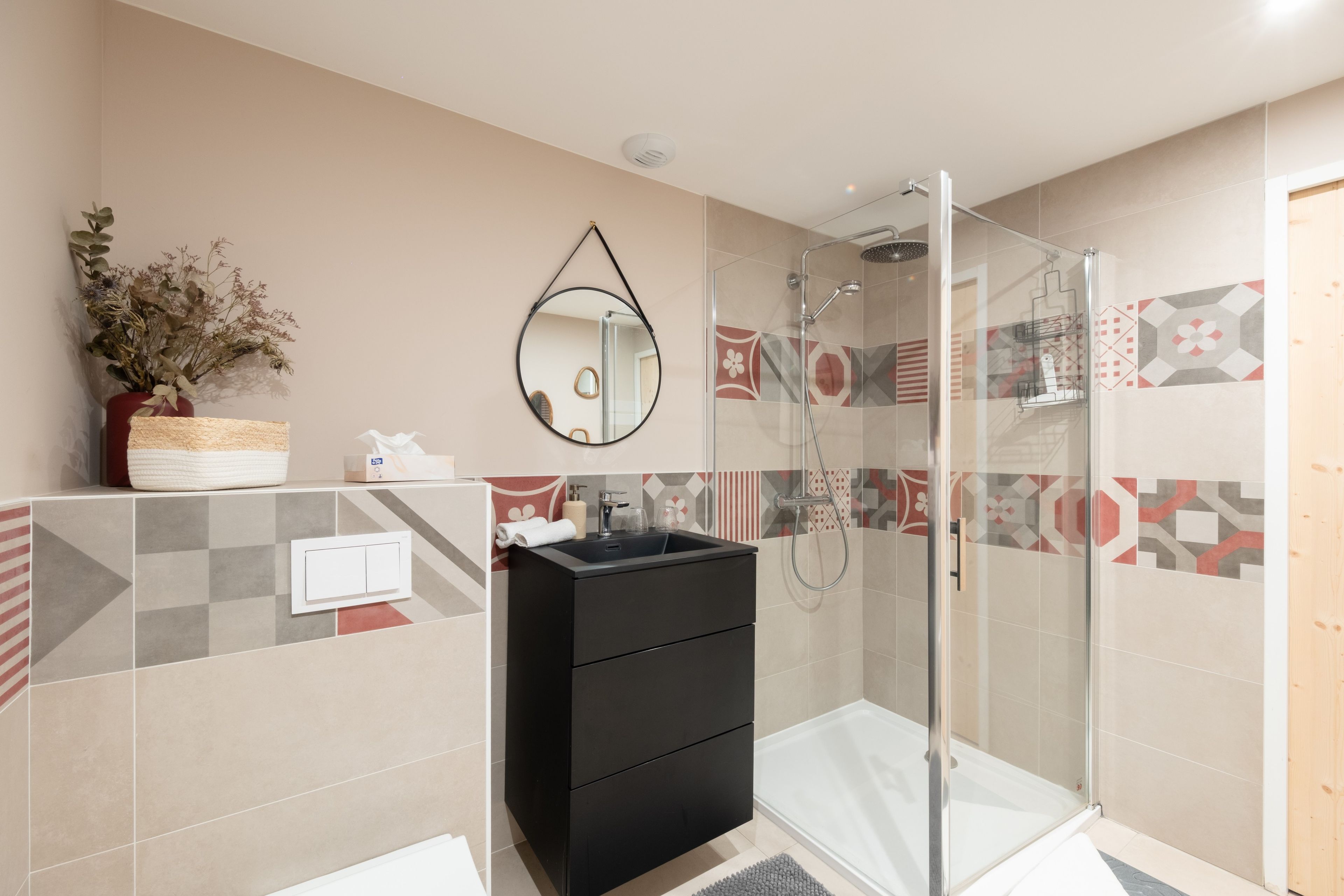 A modern bathroom with a shower, a vanity with a mirror, and patterned tiles.