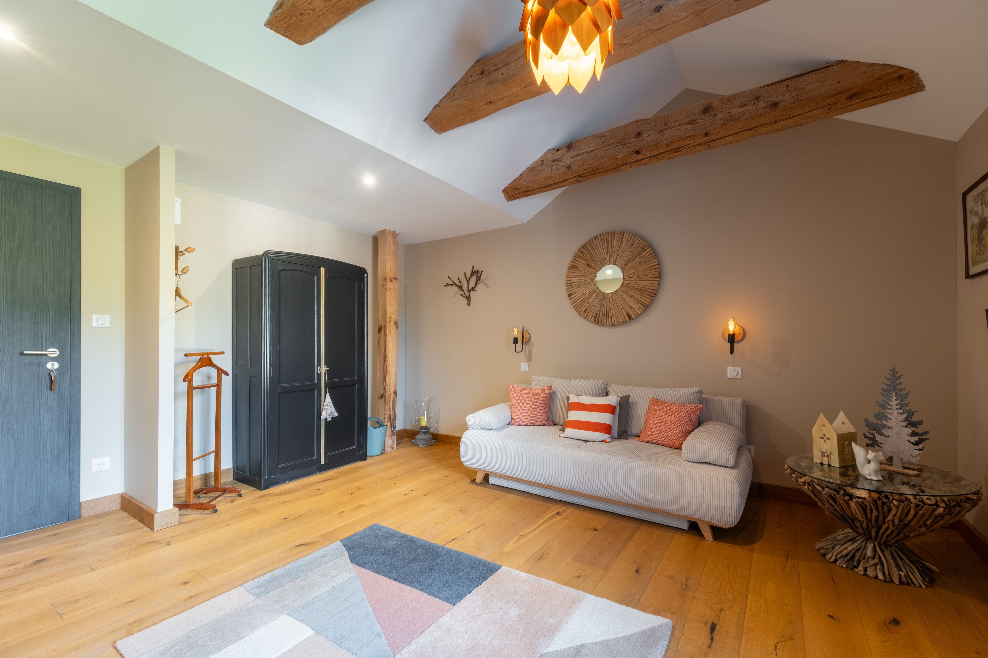 A cozy living room with a sofa, a decorative mirror, and a wooden ceiling.