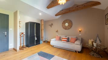 A cozy living room with a sofa, a decorative mirror, and a wooden ceiling.