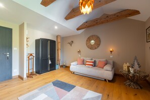 Een gezellige woonkamer met een bank, een decoratieve spiegel en een houten plafond.
