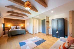 Een kamer met een bed, een kledingkast, een hanglamp en een houten plafond.