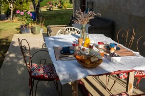 Een buiten eethoek met een tafel gedekt voor twee personen, met diverse gerechten en dranken.