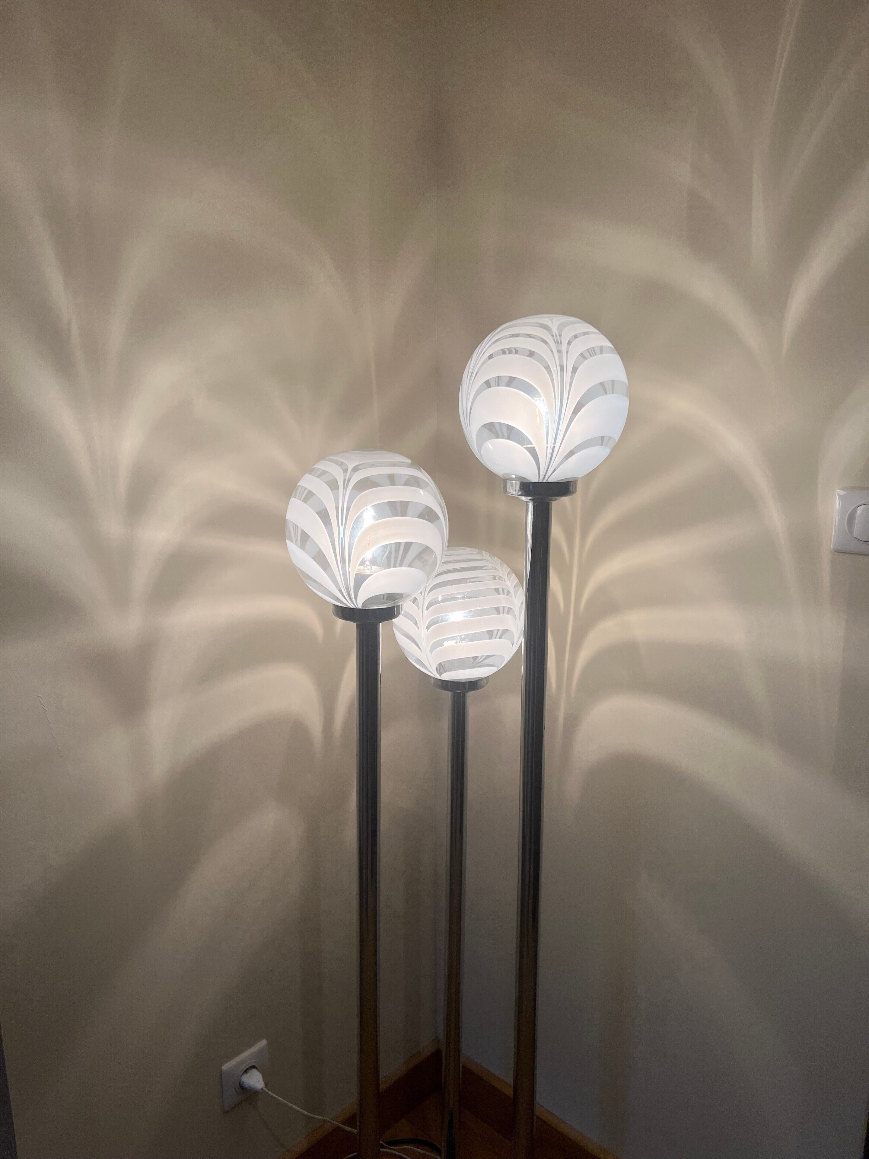 Three floor lamps with a unique design against a plain wall.