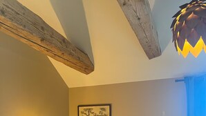 Une pièce avec des poutres en bois, une commode et trois tableaux encadrés accrochés au mur.