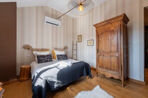 Un dormitorio con una cama, un armario de madera, una escalera y un equipo de aire acondicionado.