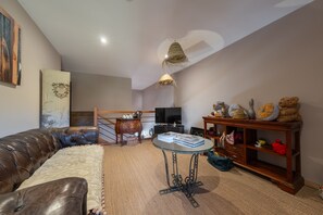 A living room with a leather sofa, a round glass coffee table, and a wooden cabinet with decorative items.
