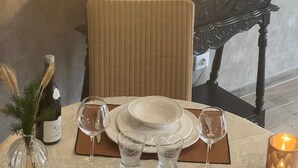 Mesa posta com pratos, copos, talheres e uma vela.