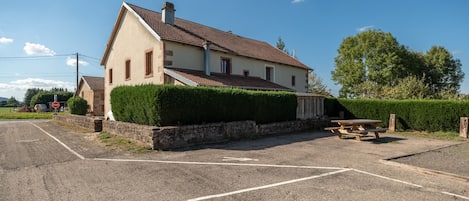 Ein zweistöckiges Haus mit einem Ziegeldach, einer Steinmauer und einem gepflegten Heckenstreifen.
