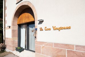 Entrada de un edificio con puerta de madera y un letrero que dice 'La Cure Vocatione'.