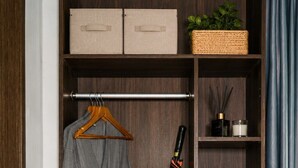 A closet with a hanging robe, a broom, folded towels, a basket, and slippers. - Arterra Haven Aonang Krabi (Krabi)