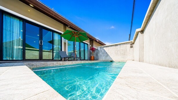 A swimming pool with clear water, a lounge area with chairs, and a large windowed room with curtains. - Arterra Haven Aonang Krabi (Krabi)