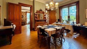 Uma sala de jantar com móveis de madeira, um candelabro e papel de parede listrado.