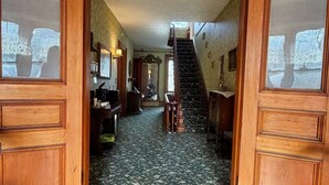 Um quarto com piso de madeira, escada e papel de parede estampado.