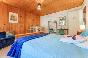 Un dormitorio con paneles de madera, una cama, un escritorio, una silla y un espejo.