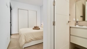 A bedroom with a bed, a wardrobe, and a bathroom with a sink and mirror. - Apartment 'Building Copenhagen, Nerja' with Shared Pool, Wi-Fi and Air Conditioning (Nerja)