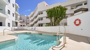 A swimming pool with clear water, surrounded by white buildings, a cactus, and a lifebuoy on the wall. - Apartment 'Building Copenhagen, Nerja' with Shared Pool, Wi-Fi and Air Conditioning (Nerja)