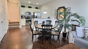Une cuisine moderne avec des meubles blancs, des appareils en acier inoxydable et un coin repas comprenant une table et des chaises en bois.