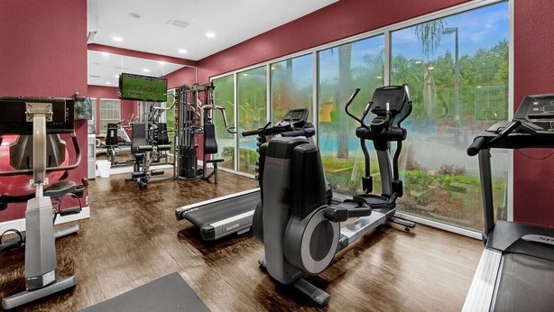 Une salle de sport équipée de machines de cardio, de matériel de musculation et dotée d’une grande fenêtre donnant sur un espace verdoyant.