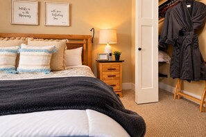 A bedroom with a bed, bedside table, lamp, framed quotes, and a robe rack. - Immaculate Cottage, Clean Hot Tub, 2 Miles to Asheville (Asheville)