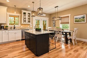 A kitchen with a central island, wooden flooring, and pendant lighting. - Exceptionally Clean Cottage with Private Hot Tub Near Asheville (Asheville)