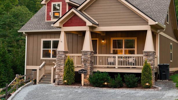A two-story house with a stone foundation, a front porch, and a small deck. - Exceptionally Clean Cottage with Private Hot Tub Near Asheville (Asheville)