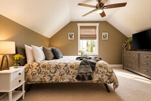 A bedroom with a bed, a nightstand, a dresser, a ceiling fan, and a window with blinds. - Exceptionally Clean Cottage with Private Hot Tub Near Asheville (Asheville)