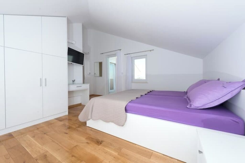 Un dormitorio con cama, armario, tocador y ventana.