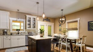 A kitchen with a central island, wooden flooring, white cabinets, and pendant lighting. - Immaculate Cottage with Private Hot Tub and Fireplace (Asheville)