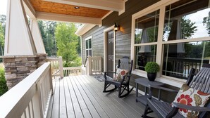 A wooden deck with two rocking chairs and a potted plant. - Immaculate Cottage with Private Hot Tub and Fireplace (Asheville)