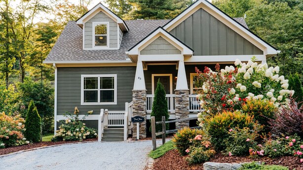 A two-story house with a stone porch, a front door, and a mailbox. - Immaculate Cottage with Private Hot Tub and Fireplace (Asheville)