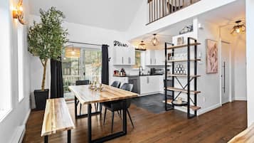 Una cucina moderna con mobili bianchi, un tavolo da pranzo in legno e una scaffalatura in metallo nero.
