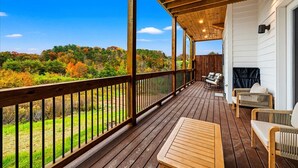 A wooden deck with a view of a forest, a fireplace, and outdoor seating. - *Luxurious 6BD Lodge w/ POOL | Hot Tub + Theater* (Sevierville)