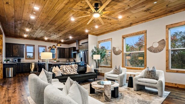 A spacious living area with a wooden ceiling, large windows, and a modern kitchen in the background. - *Luxurious 6BD Lodge w/ POOL | Hot Tub + Theater* (Sevierville)