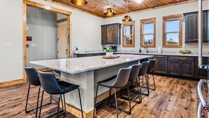 A modern kitchen with a large island, dark wooden cabinets, and pendant lighting. - *Luxurious 6BD Lodge w/ POOL | Hot Tub + Theater* (Sevierville)
