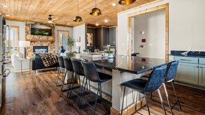 Una cocina moderna con una isla central, taburetes de bar e iluminación colgante.