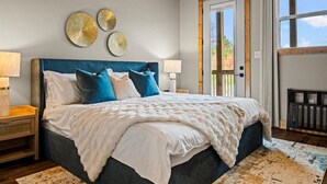 Un dormitorio con una cama grande, dos lámparas de noche y vistas al exterior a través de una puerta.