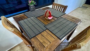 Une table de salle à manger en bois, surmontée d’un set de table à carreaux noirs et blancs, et entourée de chaises en bois.