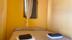 Une chambre avec un lit, une fenêtre avec un rideau et des serviettes sur le lit.