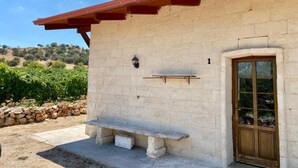 Un bâtiment à l’extérieur en pierre, avec une porte en bois et un banc à l’extérieur.