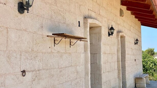 Un bâtiment en pierre avec une étagère en bois et deux lanternes fixées au mur.