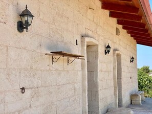 Ein Steinhaus mit einem hölzernen Regal und zwei Wandleuchten.
