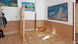 A room with a tiled floor, a wooden bench, and three framed landscape paintings on the walls.