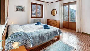 A bedroom with a bed, a dresser, a radiator, a window with a view, and a painting on the wall.