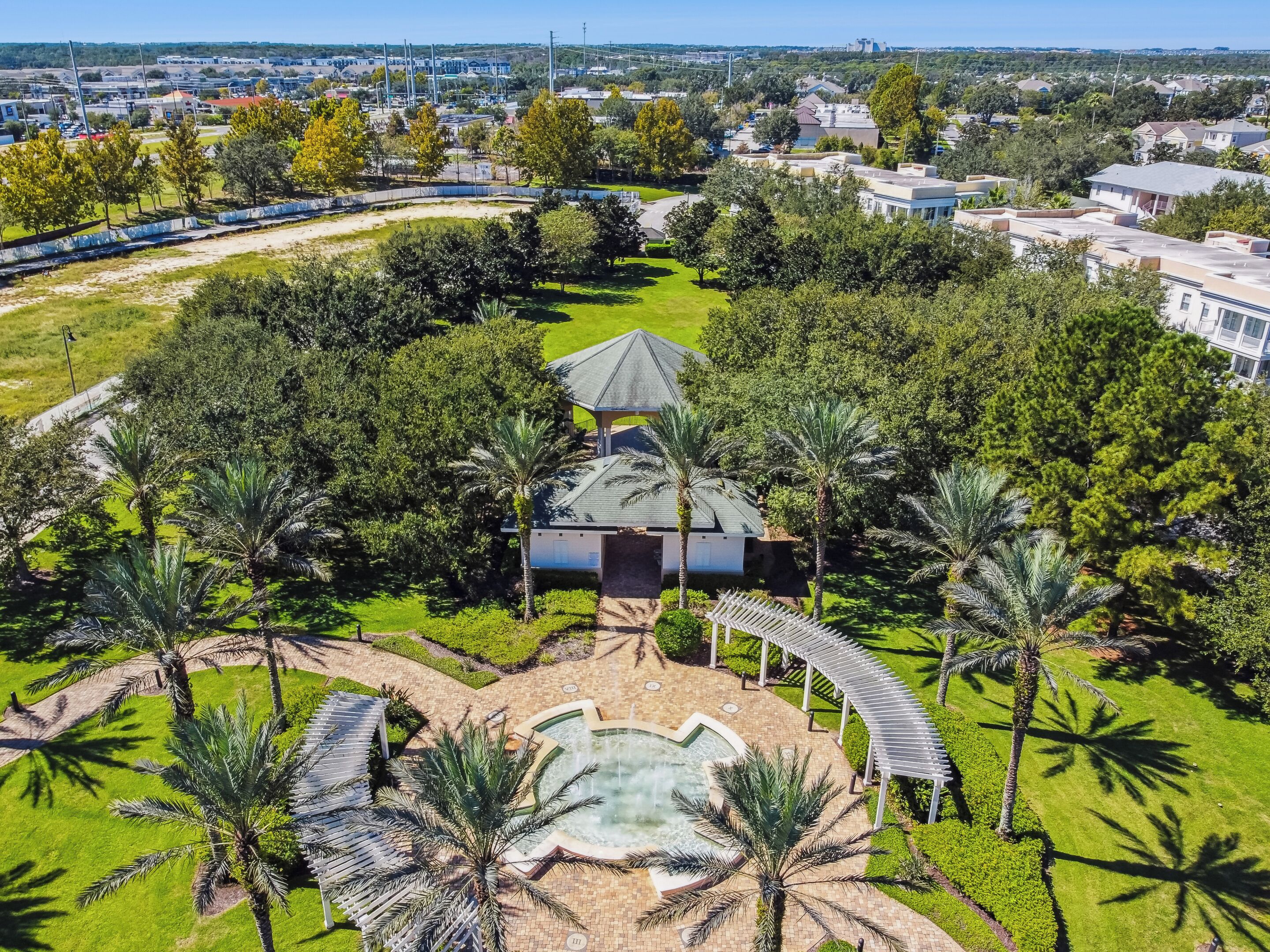 An aerial view of a resort with a central building, palm trees, and a swimming pool.